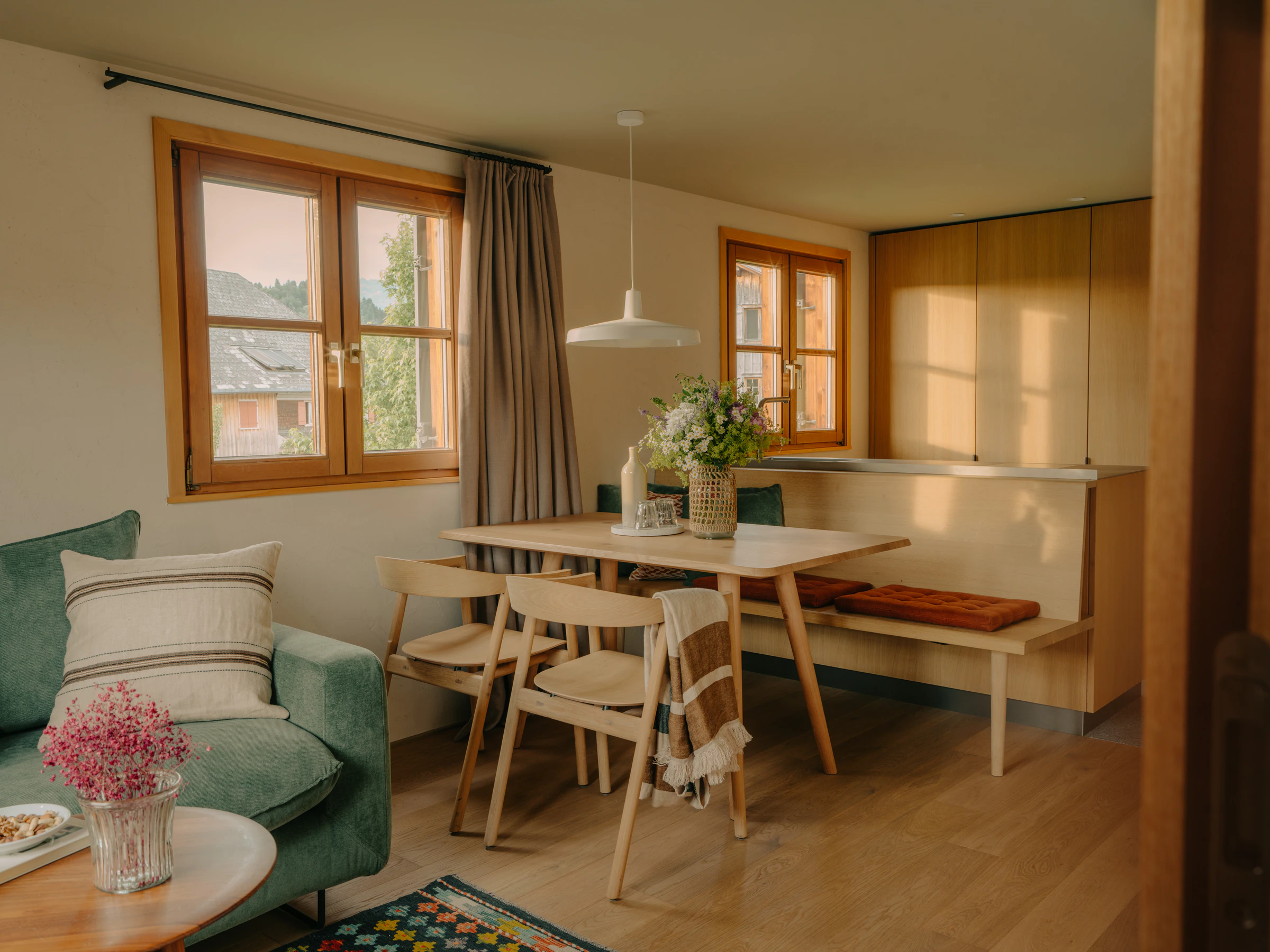Suite im Wälderhaus mit Holzböden, Essplatz, Sofa und Fenstern zum Dorf.
