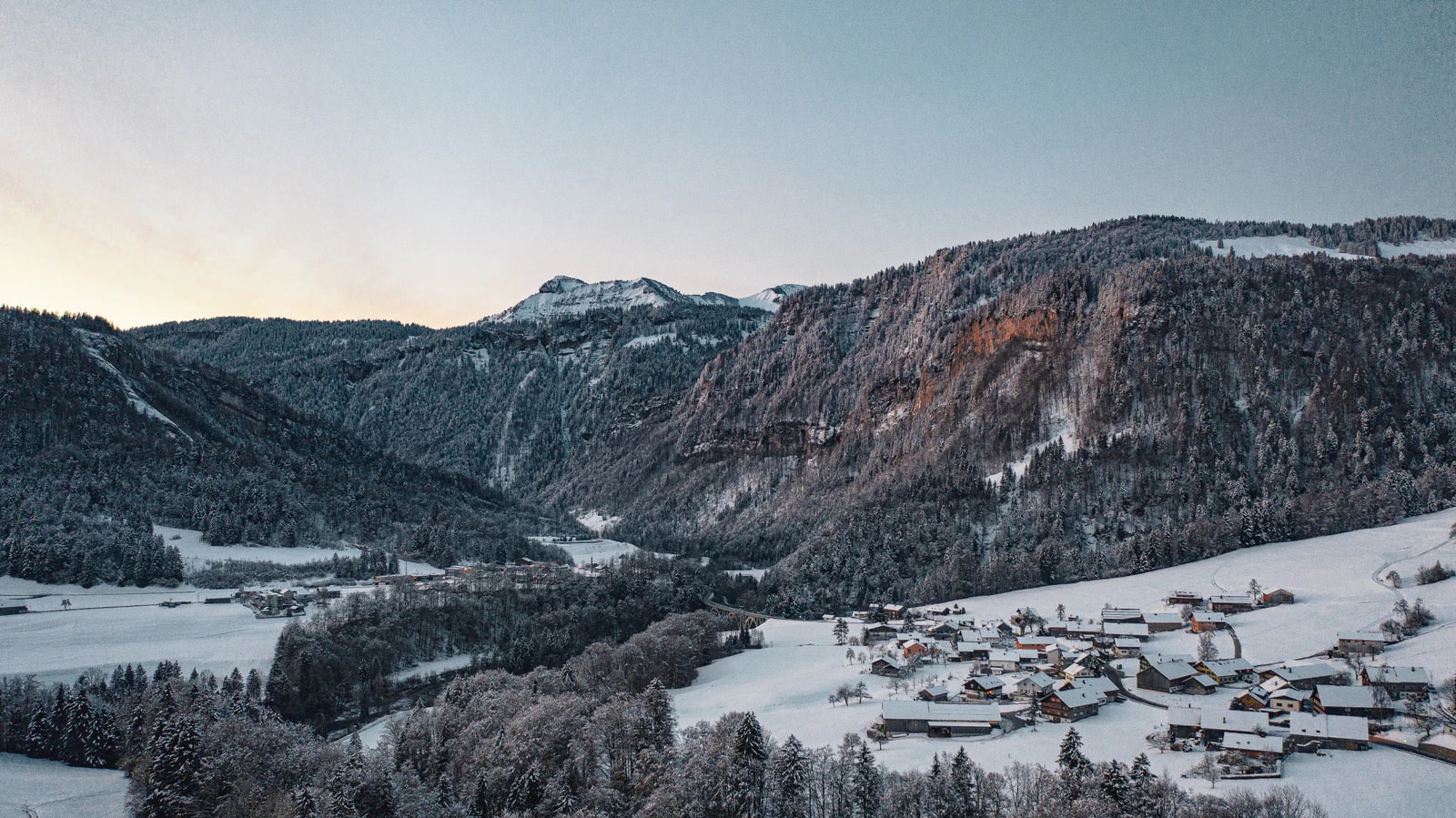 Verschneite Hügel und Dorf im Bregenzerwald.