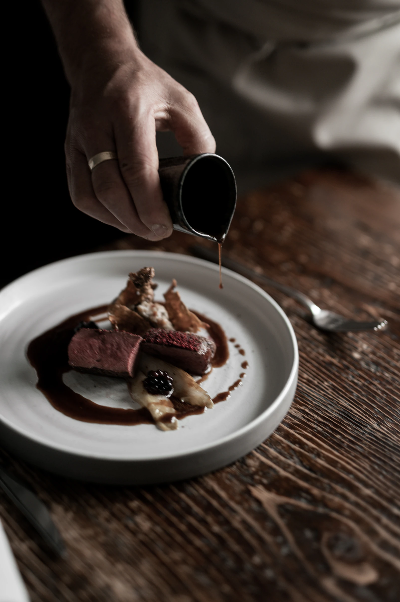 Sauce being poured over a plated dish in the Reichhalter kitchen