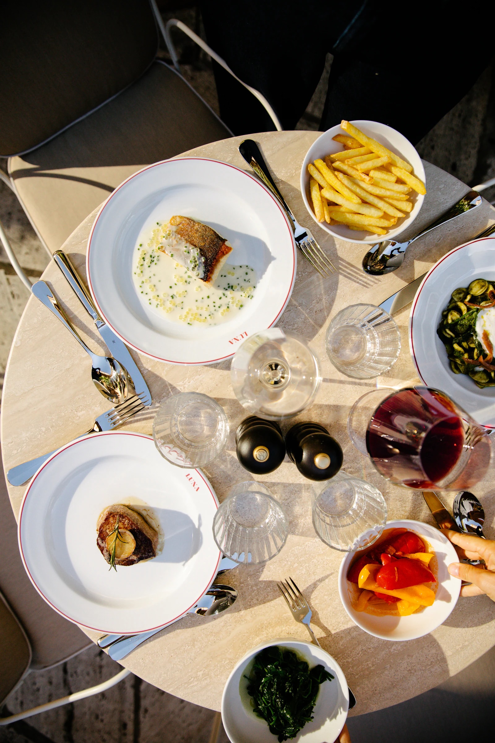 Mehrere Teller, Pommes frites und Getränke auf einem runden Tisch im Luna, von oben