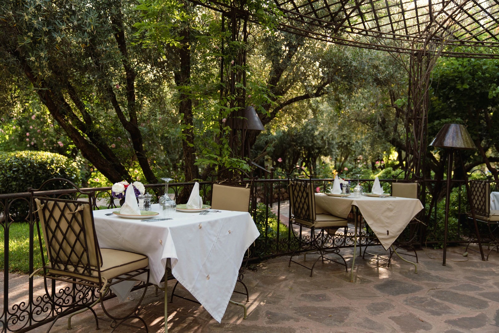 Restaurantterrasse mit gedeckten Tischen unter Bäumen.