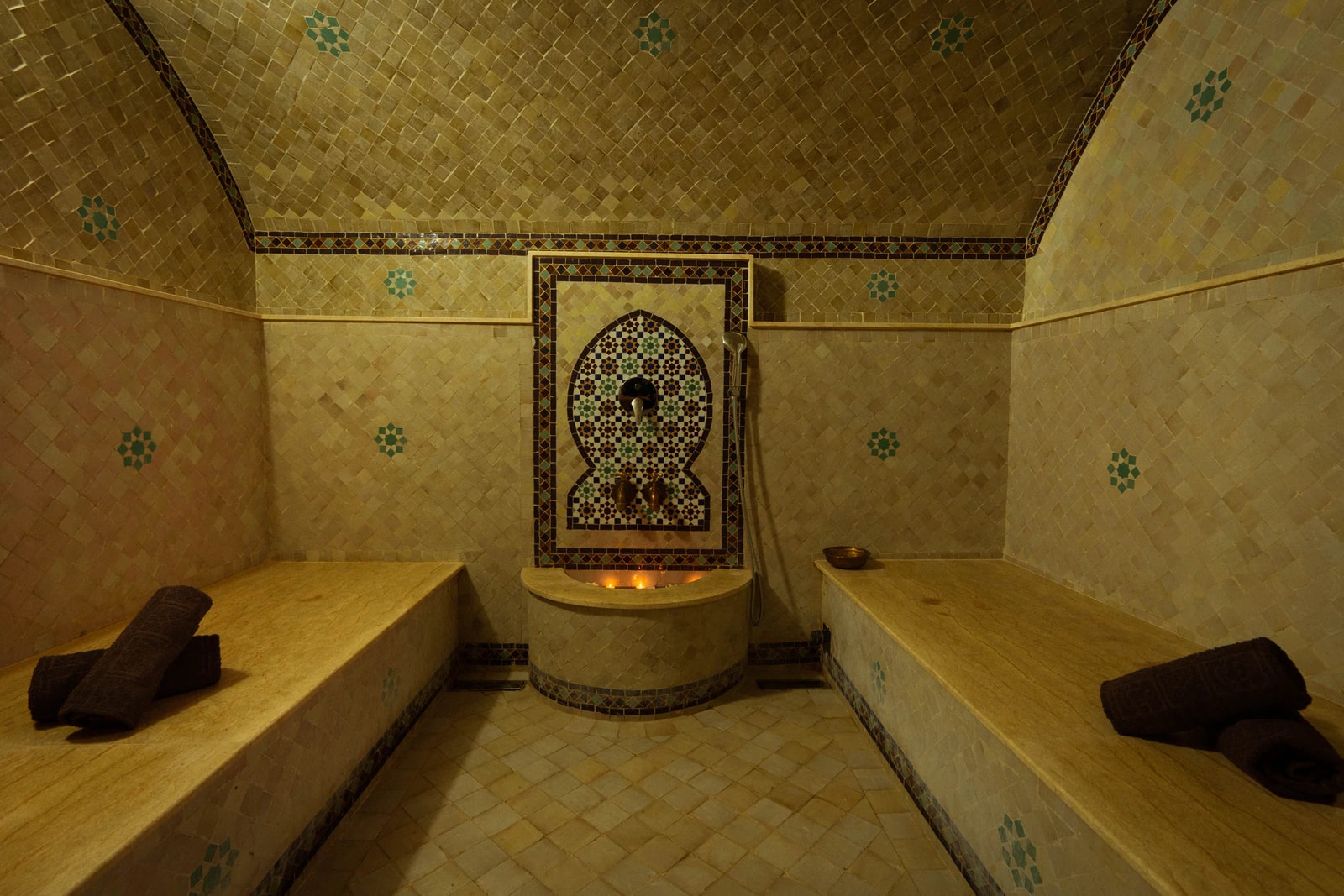Hammam mit gefliestem Gewölbe, Steinbänken und Brunnen.