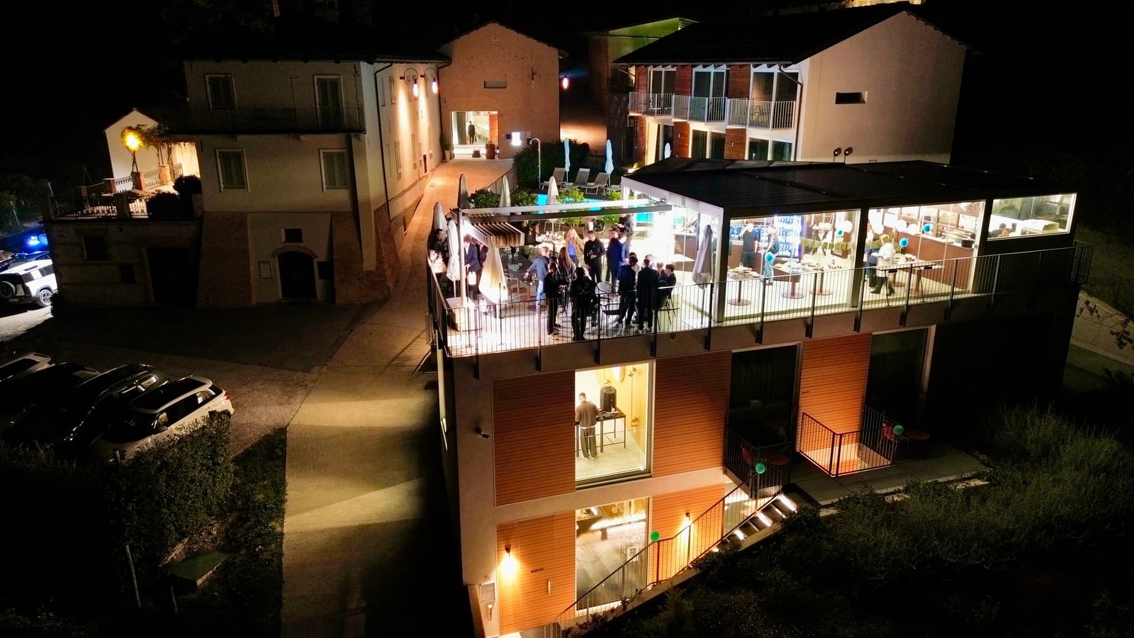 Das Haus bei Nacht von oben, die verglaste Sky Bar ist beleuchtet und voller Gäste.