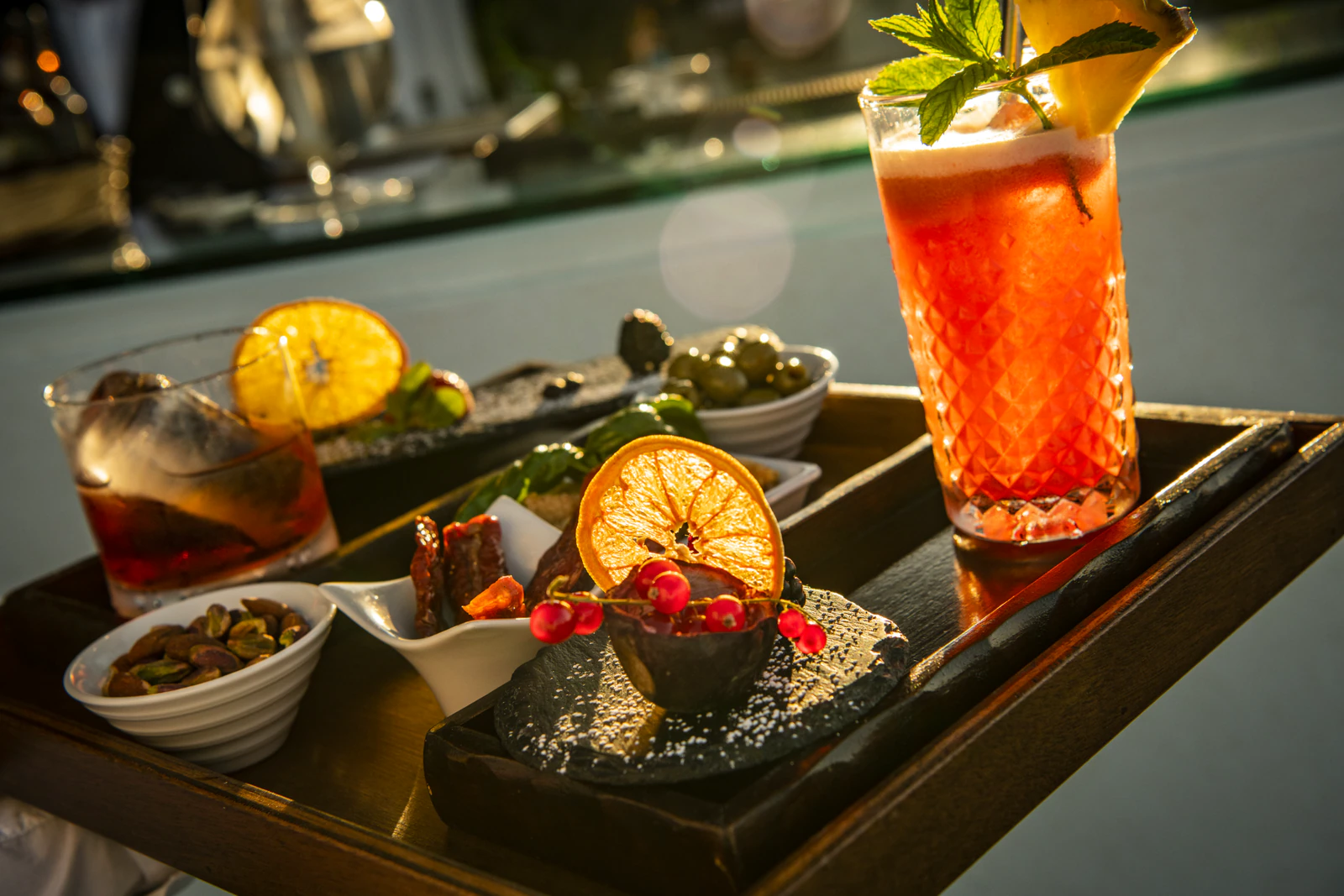 Aperitif mit zwei Cocktails und kleinen Häppchen auf einem Tablett.
