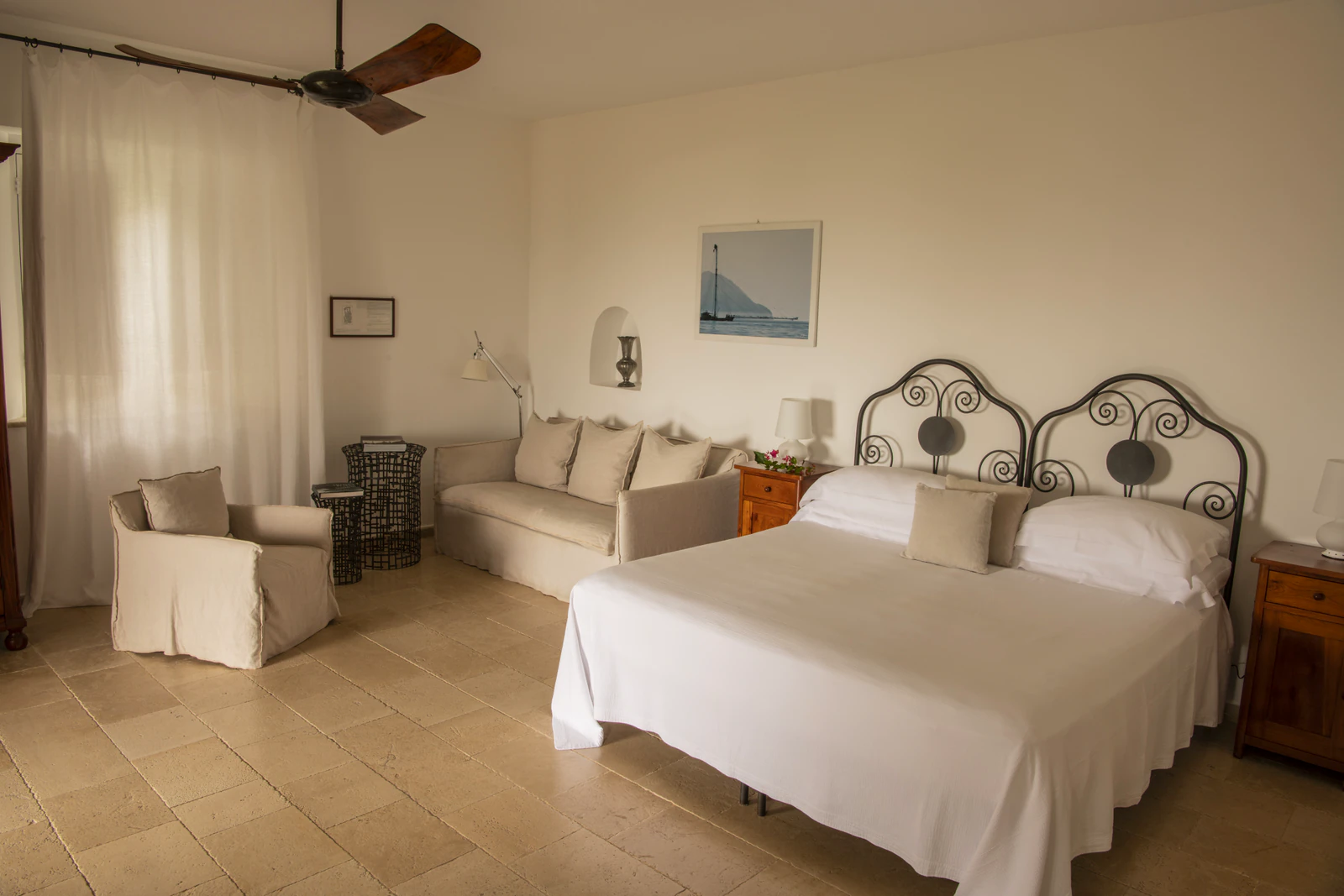 Executive-Zimmer mit schmiedeeisernem Bett, Sofa und Deckenventilator.