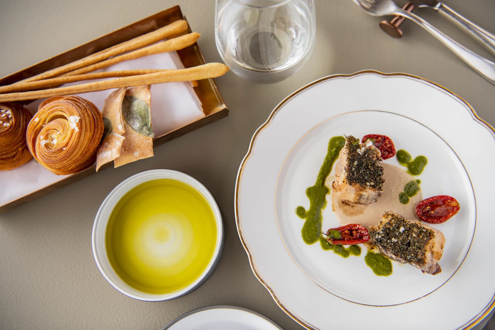 Gedeckter Tisch mit Fischgericht, Olivenöl und Brot.