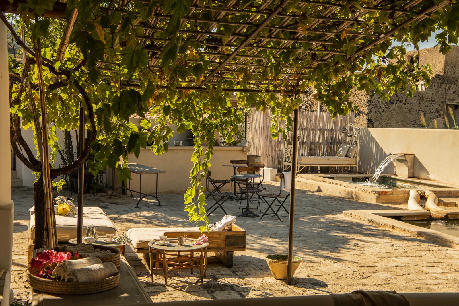 Spa-Hof unter einer Weinlaube mit Liegeplätzen und Wasserspeier.