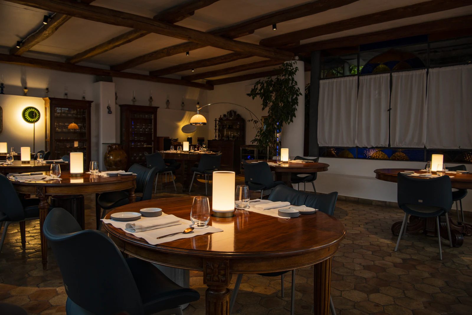 Veranda des Restaurants mit dunklen Holzbalken und gedeckten Tischen.