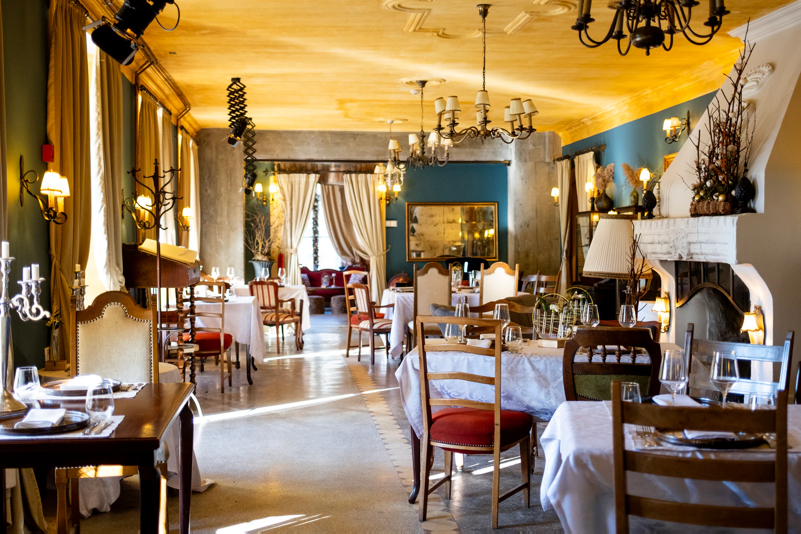 Restaurant mit Kronleuchtern, gedeckten Tischen und Kamin.