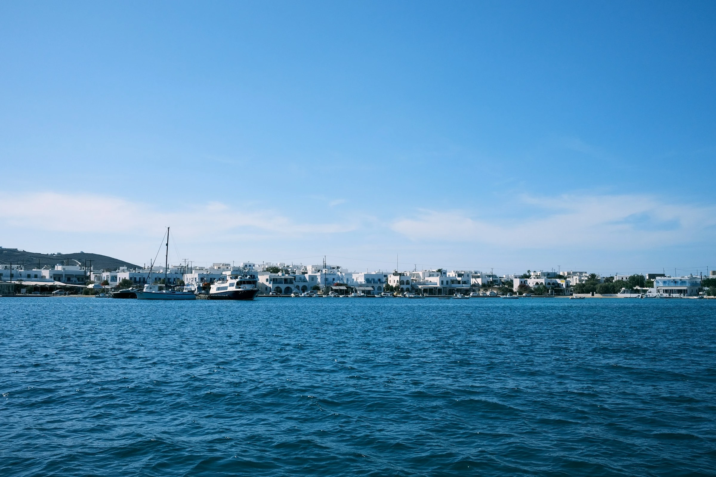 Die weiße Häuserzeile am Hafen von Antiparos, vom Wasser aus gesehen. Wenige Schritte von hier liegt Elia Kafenes. Foto: Patrick Lalonde / Unsplash