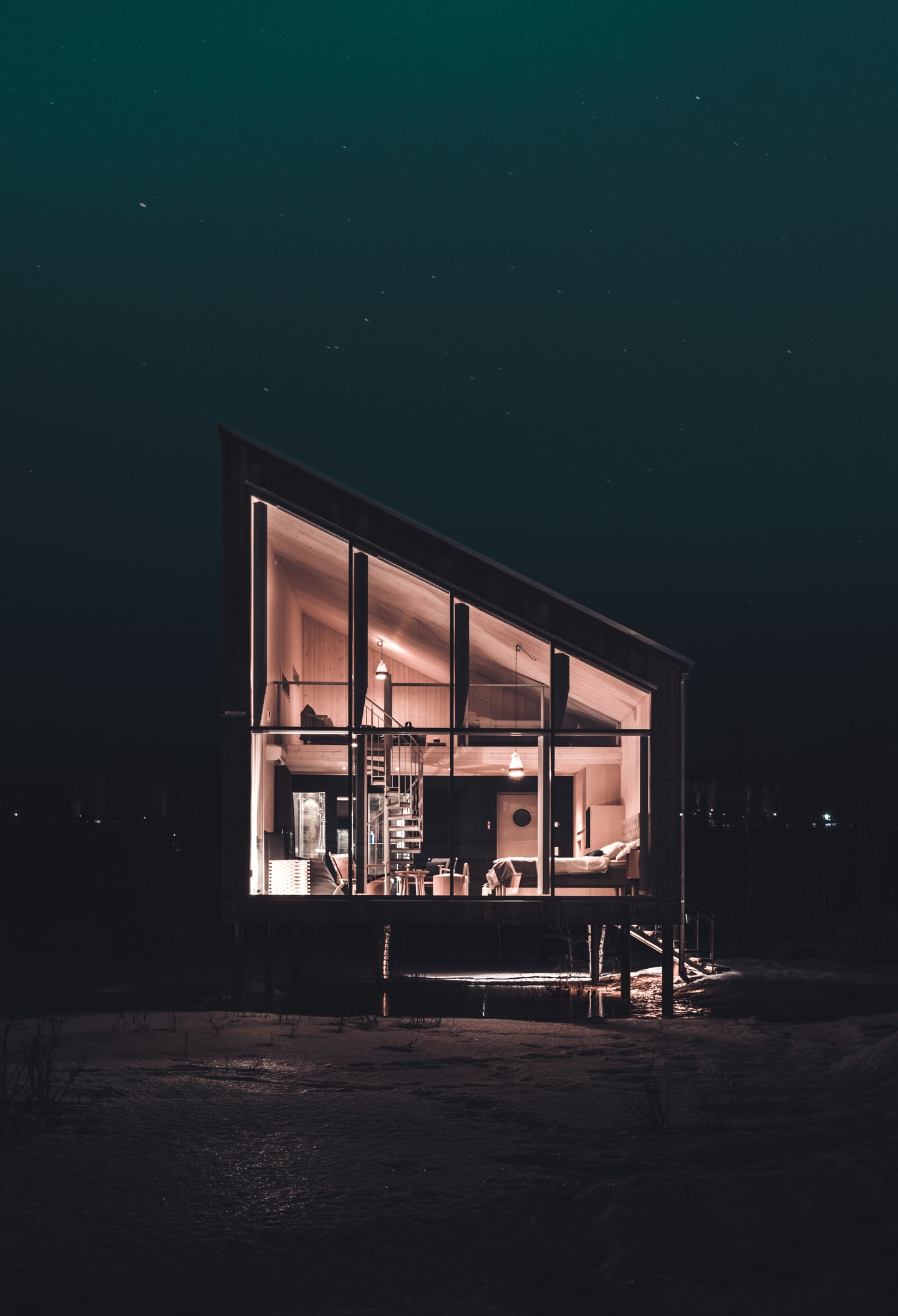 Arctic Bath — beleuchtete Landkabine bei Nacht über dem Fluss