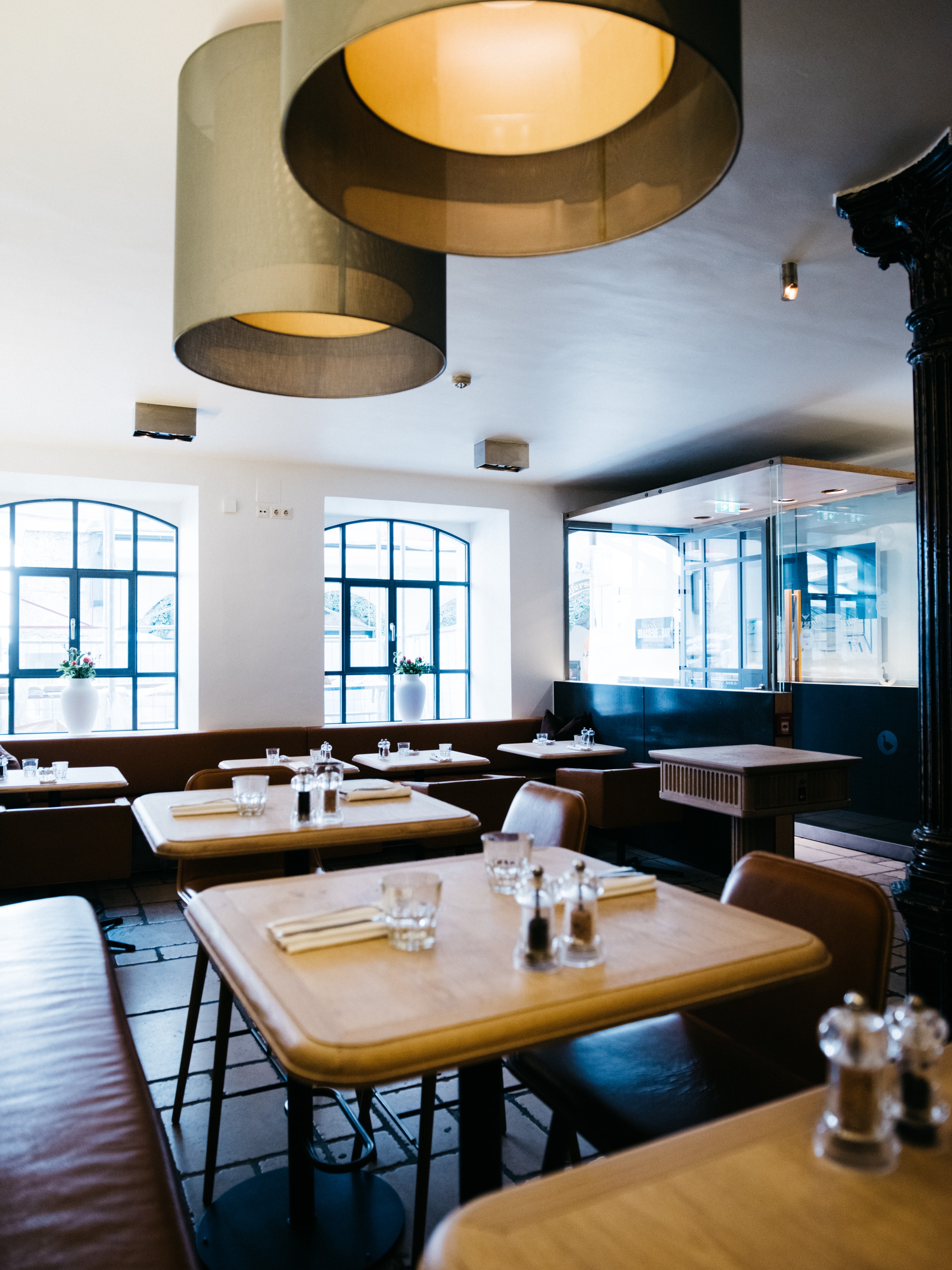 Arthotel Blaue Gans — helle Brasserie mit Ledersitzbänken, Holztischen und Rundbogenfenstern