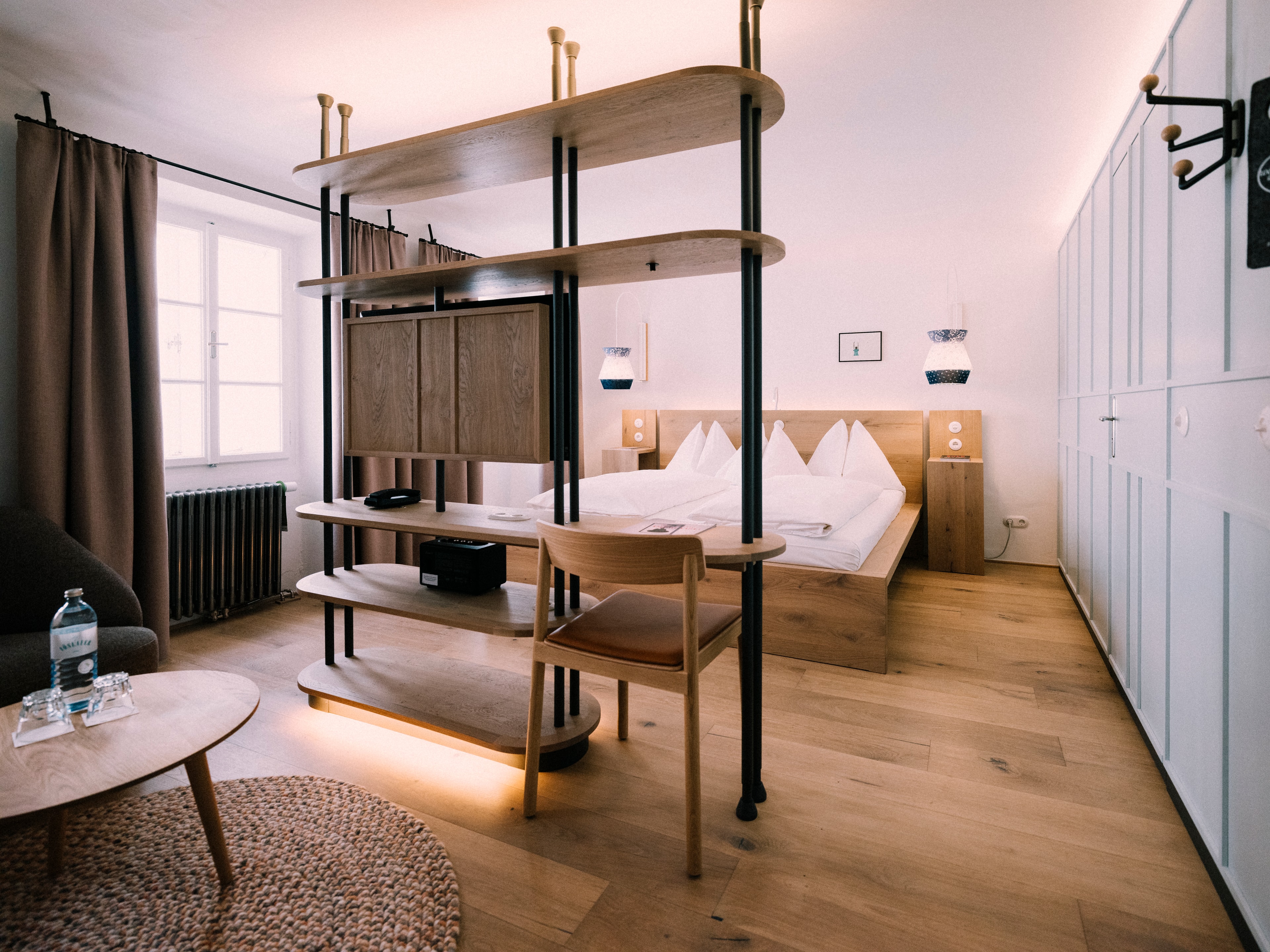 Arthotel Blaue Gans — Zimmer mit Eichenholz-Raumteiler, Bett und historischem Heizkörper