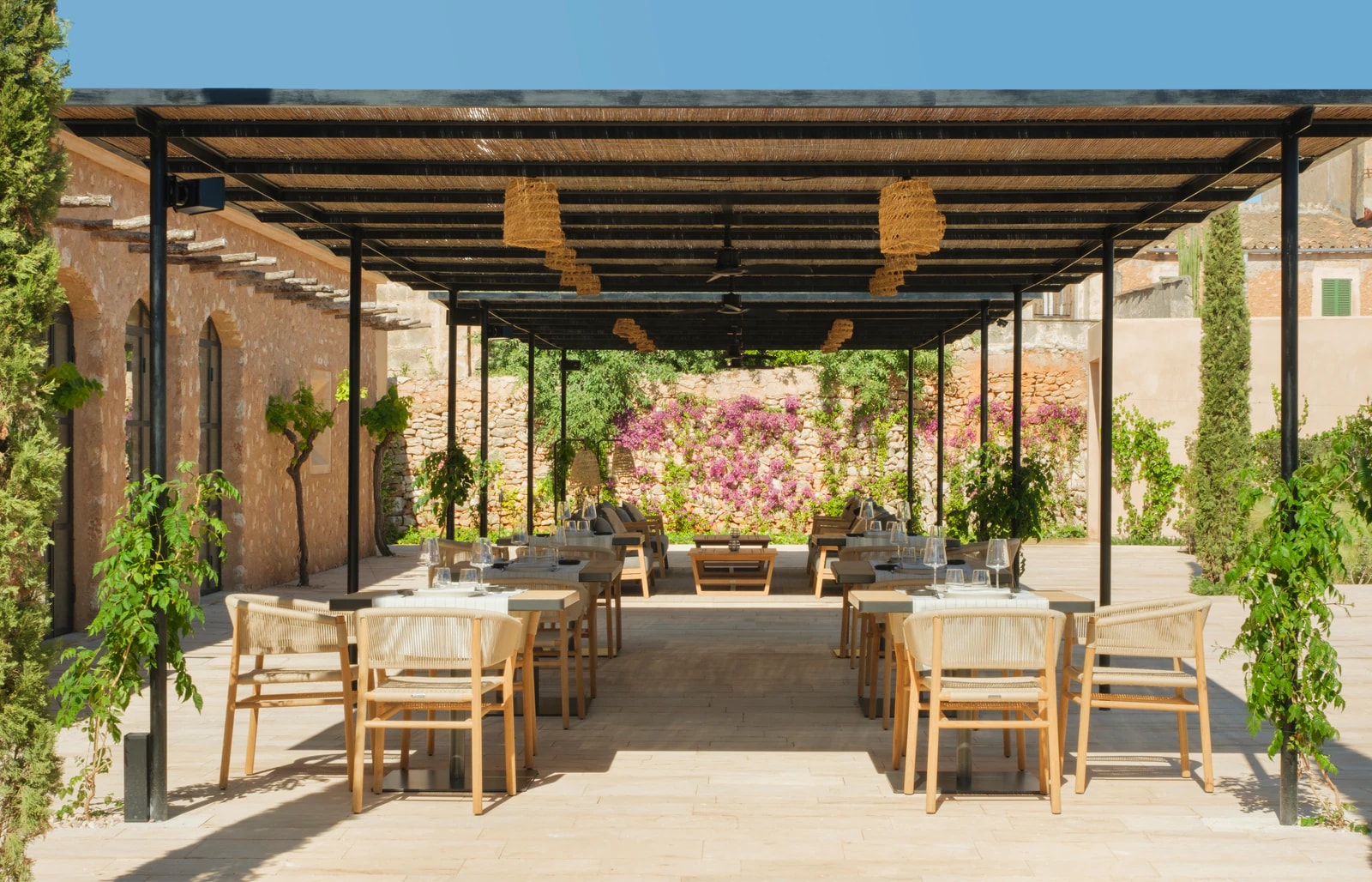 Pergola von La Fresca mit Tischen und Stühlen, umgeben von Pflanzen und Bougainvillea. Foto: Can Ferrereta
