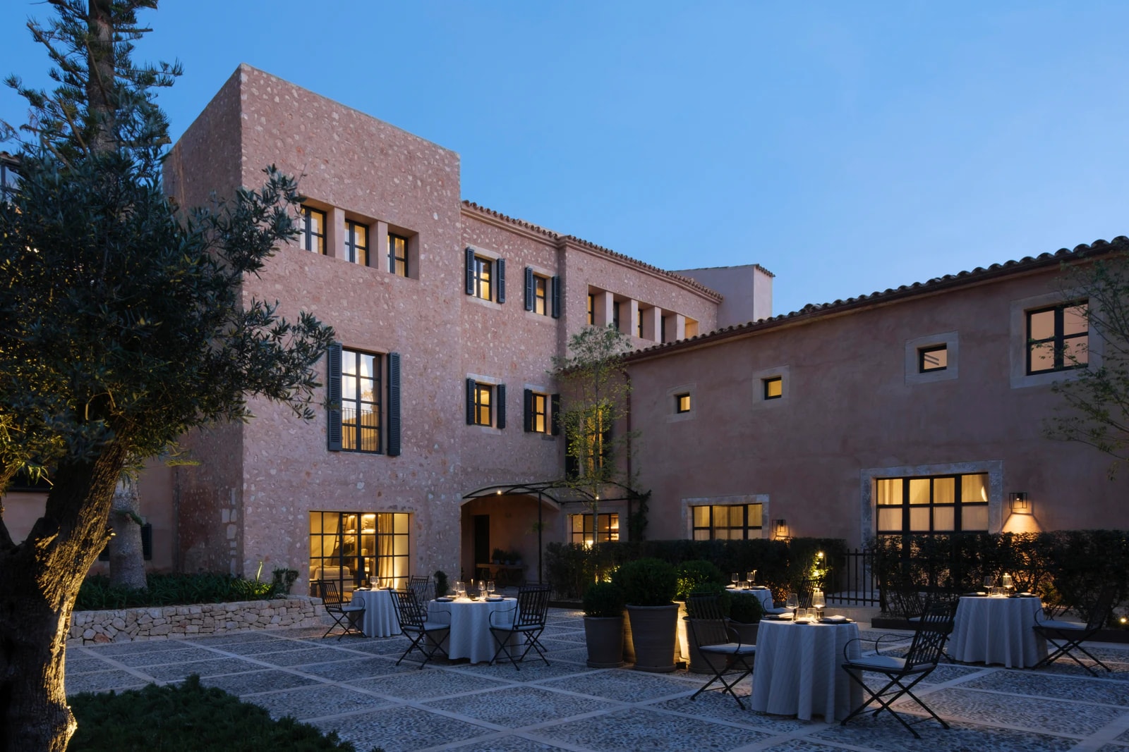 Innenhof des Restaurants Ocre am Abend mit gedeckten Tischen zwischen Sandsteinfassaden. Foto: Can Ferrereta