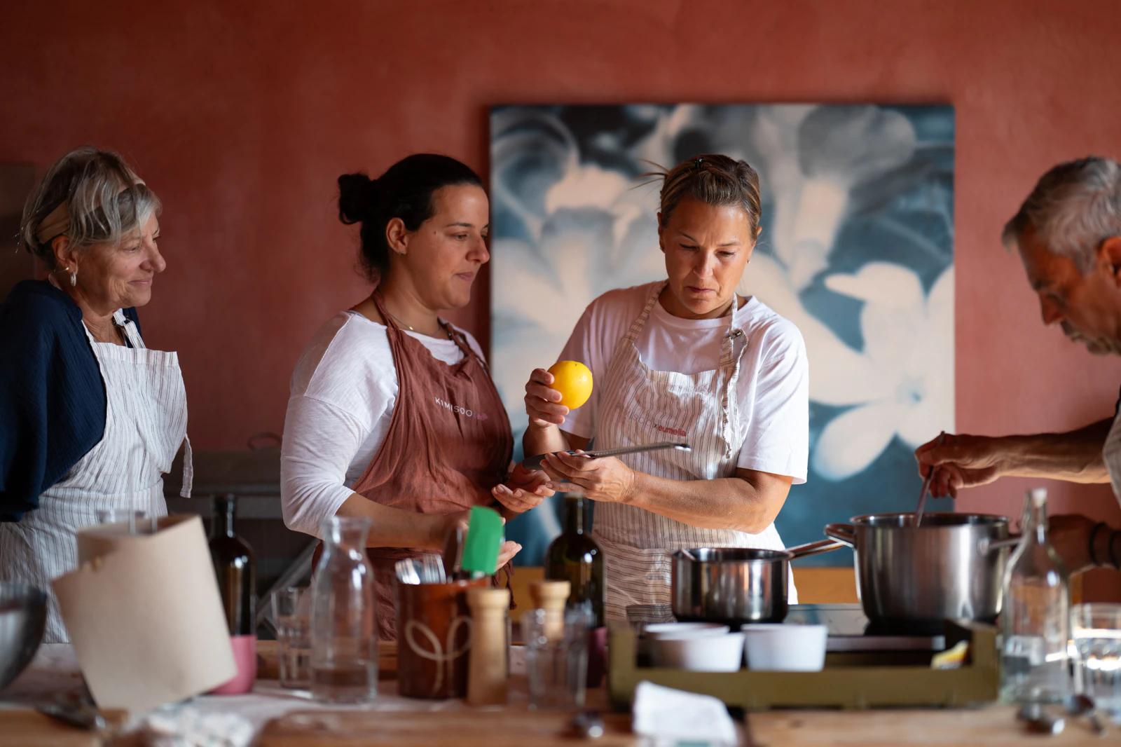 A cooking class in a red-walled room, with participants and the cook at the table. Photo: Eumelia