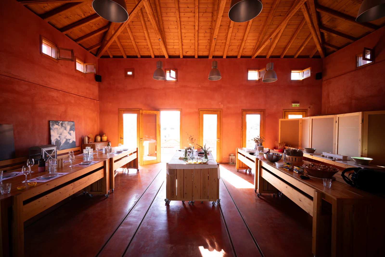 A tall room with a timber roof, red walls and long tables for the cooking classes. Photo: Eumelia
