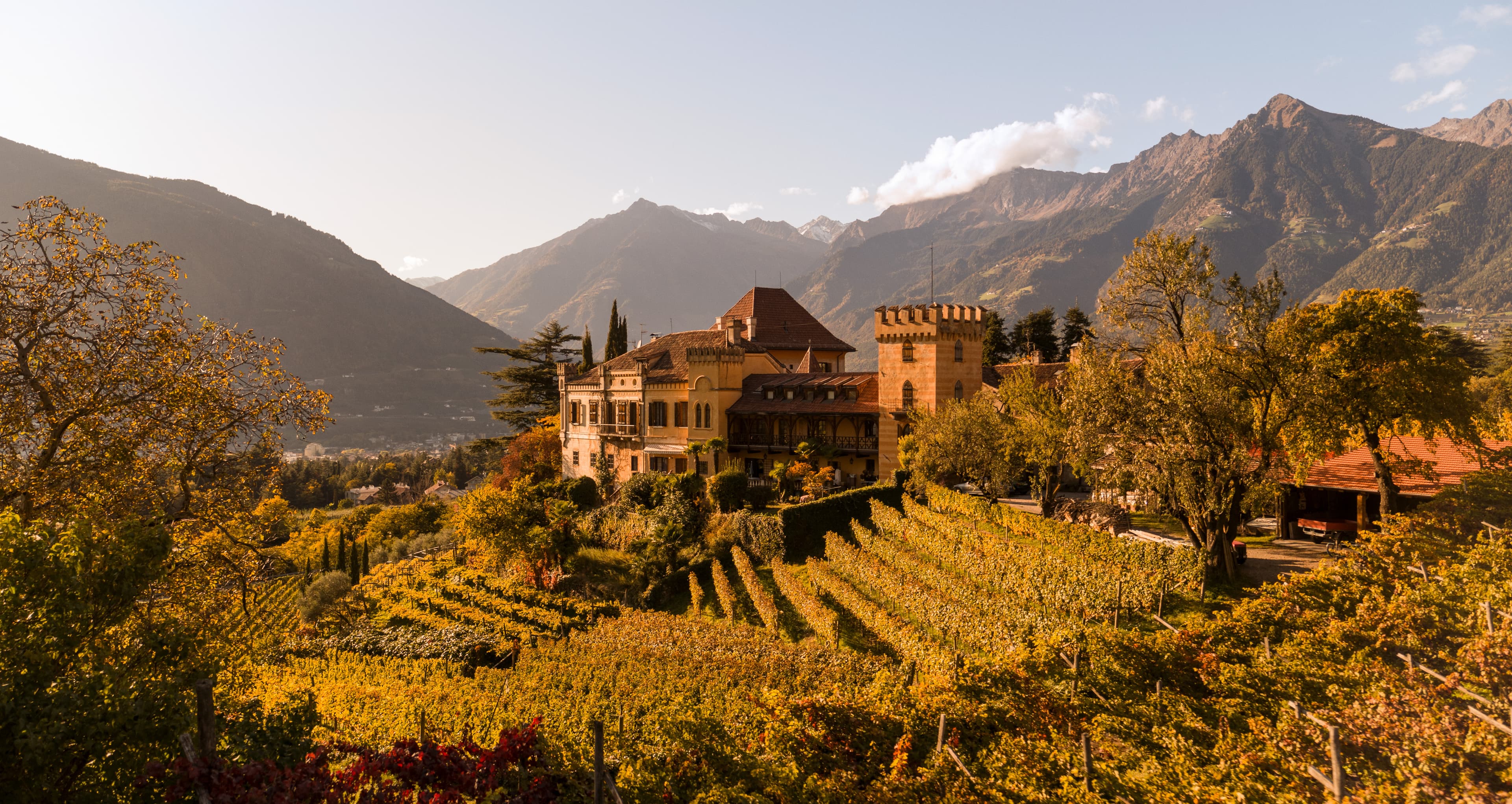 Meran — Schloss Rametz inmitten herbstlicher Weinberge mit Bergpanorama