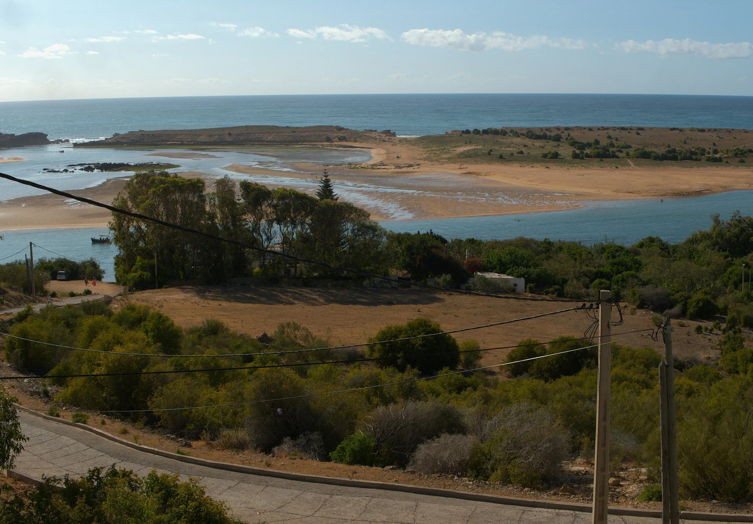 The lagoon at Oualidia, with the sandbar and the open Atlantic beyond. People swim on the calm lagoon side. Photo: Anas Ettaoudi / Unsplash