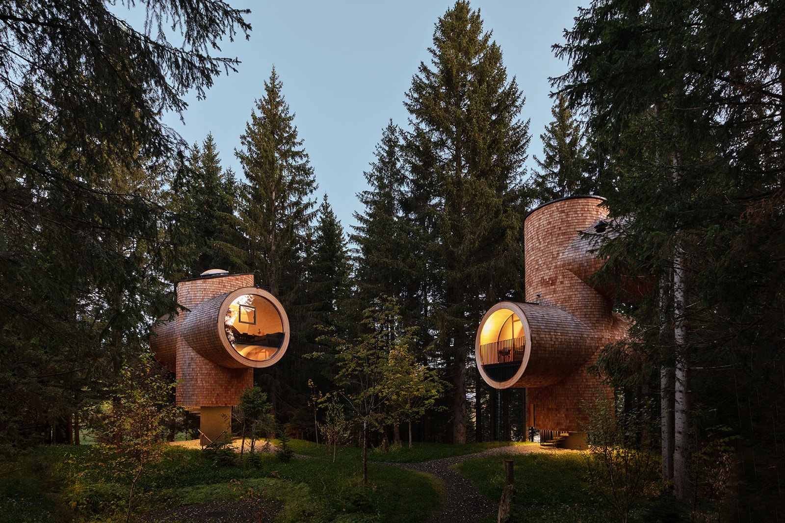 Treehouses among spruce trees at dusk. Photo: Steirereck am Pogusch