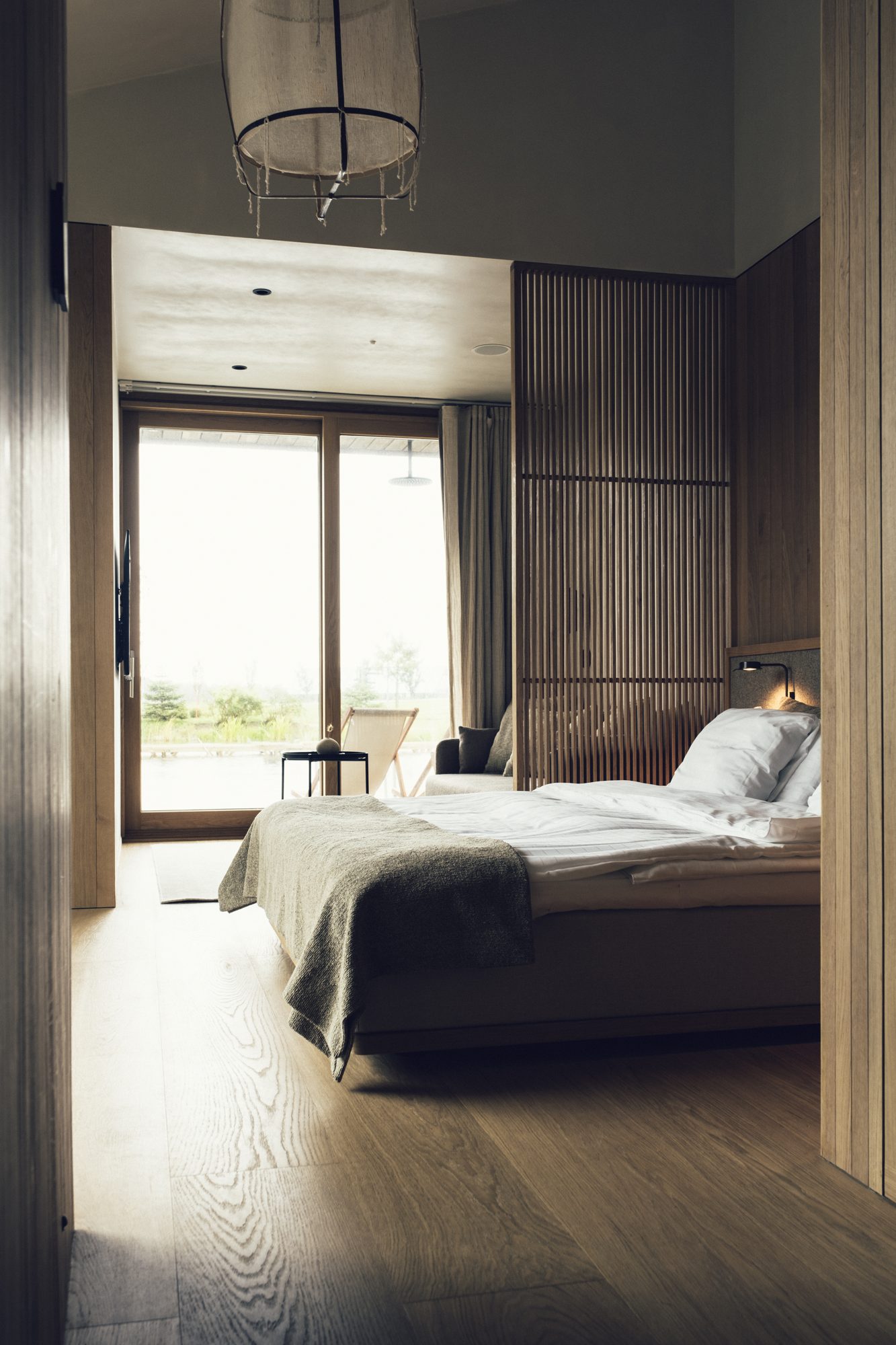 Ästad Vingård — Sjöparken-Zimmer mit Bett, warmem Holz und Fenstern zur Landschaft