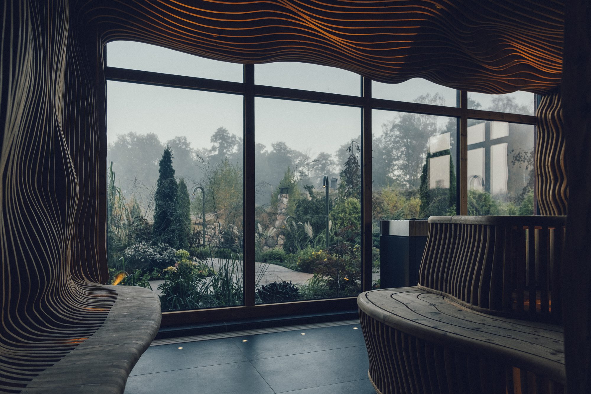 Sinnenas Spa, Ästad Vingård — geschwungene Holzsauna mit Panoramafenster zum Spa-Garten