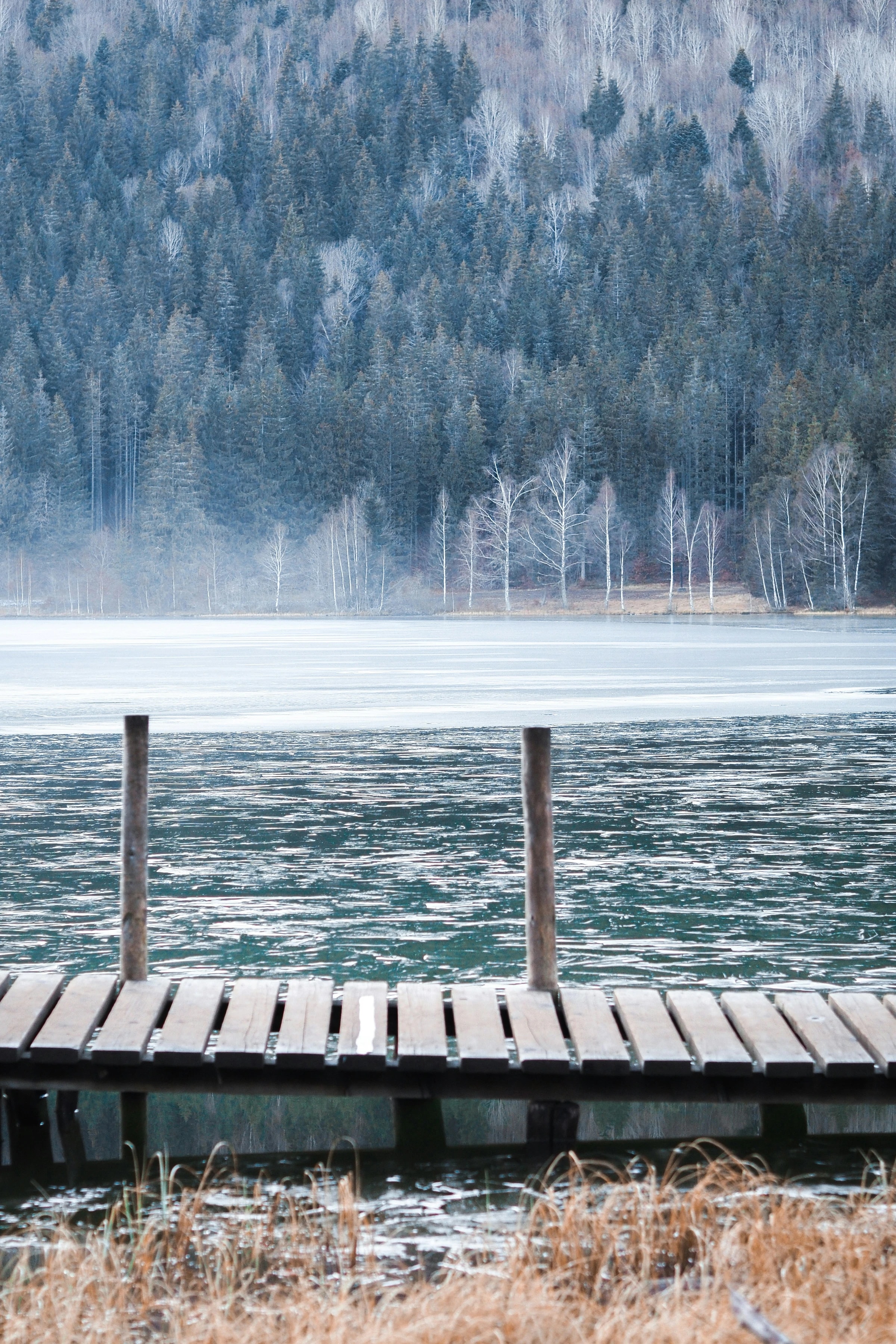 A wooden jetty on Lake Saint Ana in winter, the water partly covered in ice. Photo: Lawrence Chismorie / Unsplash
