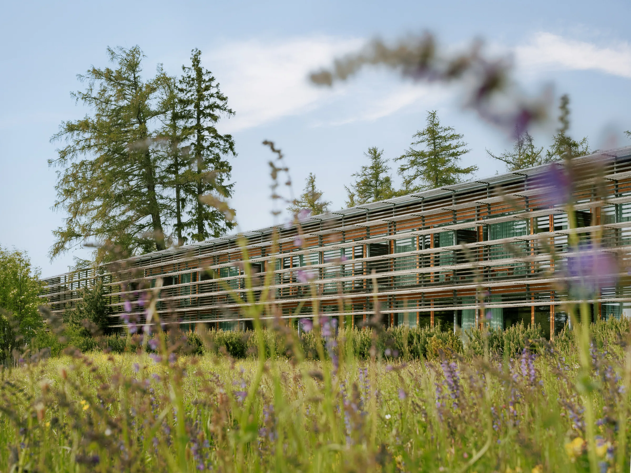 The horizontal larch-wood building of vigilius mountain resort set in alpine meadow on the Vigiljoch, South Tyrol.