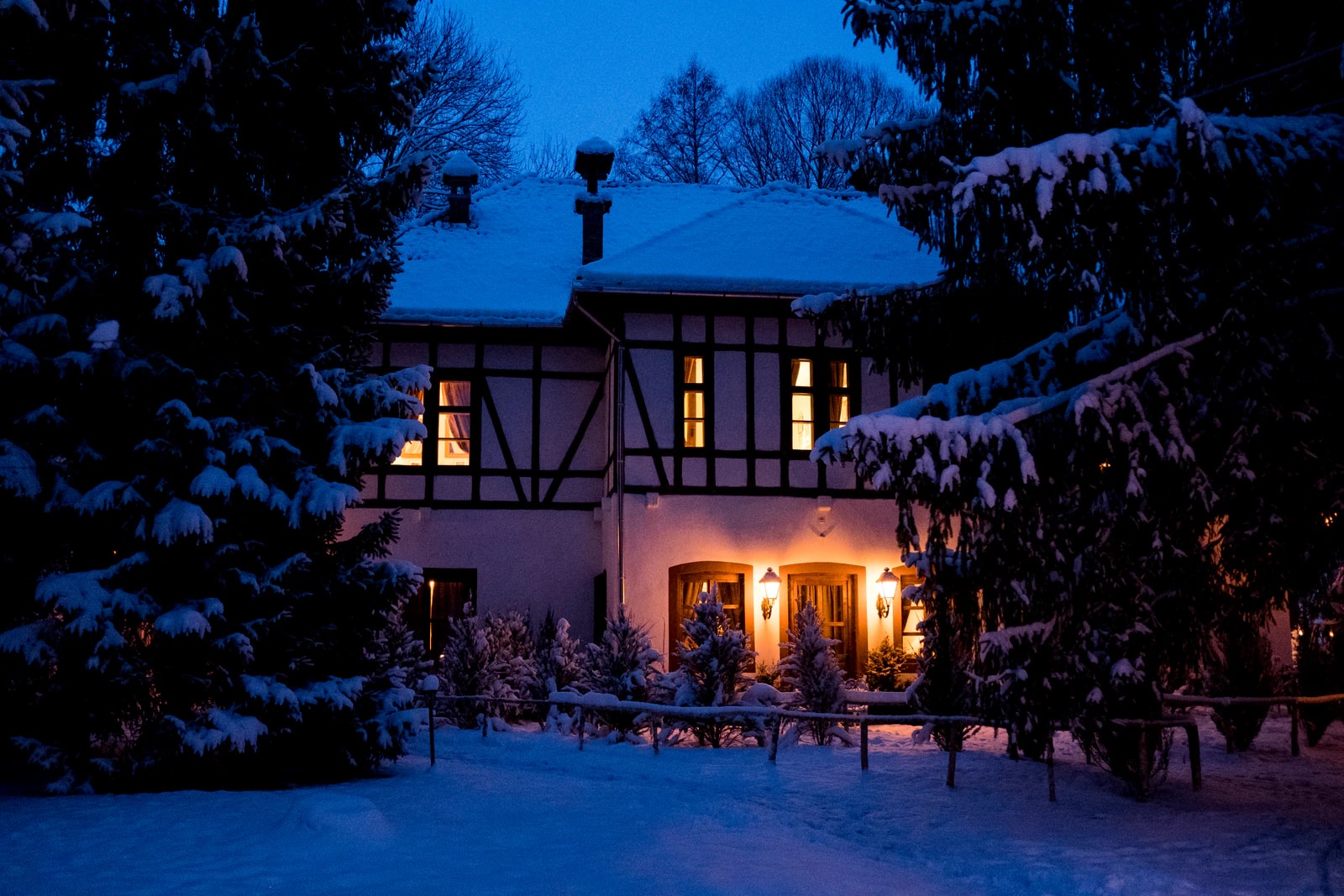 A lit half-timbered guest house in snowy woods at dusk. Photo: Pauline Roy Chowdhury / Zabola Estate