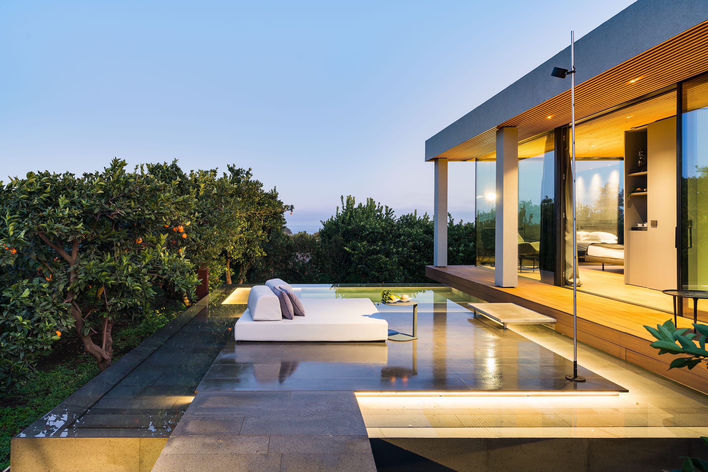 ZASH — Pool Villa mit raumhohen Glaswänden und Blick auf Baum und Rasen in der Dämmerung